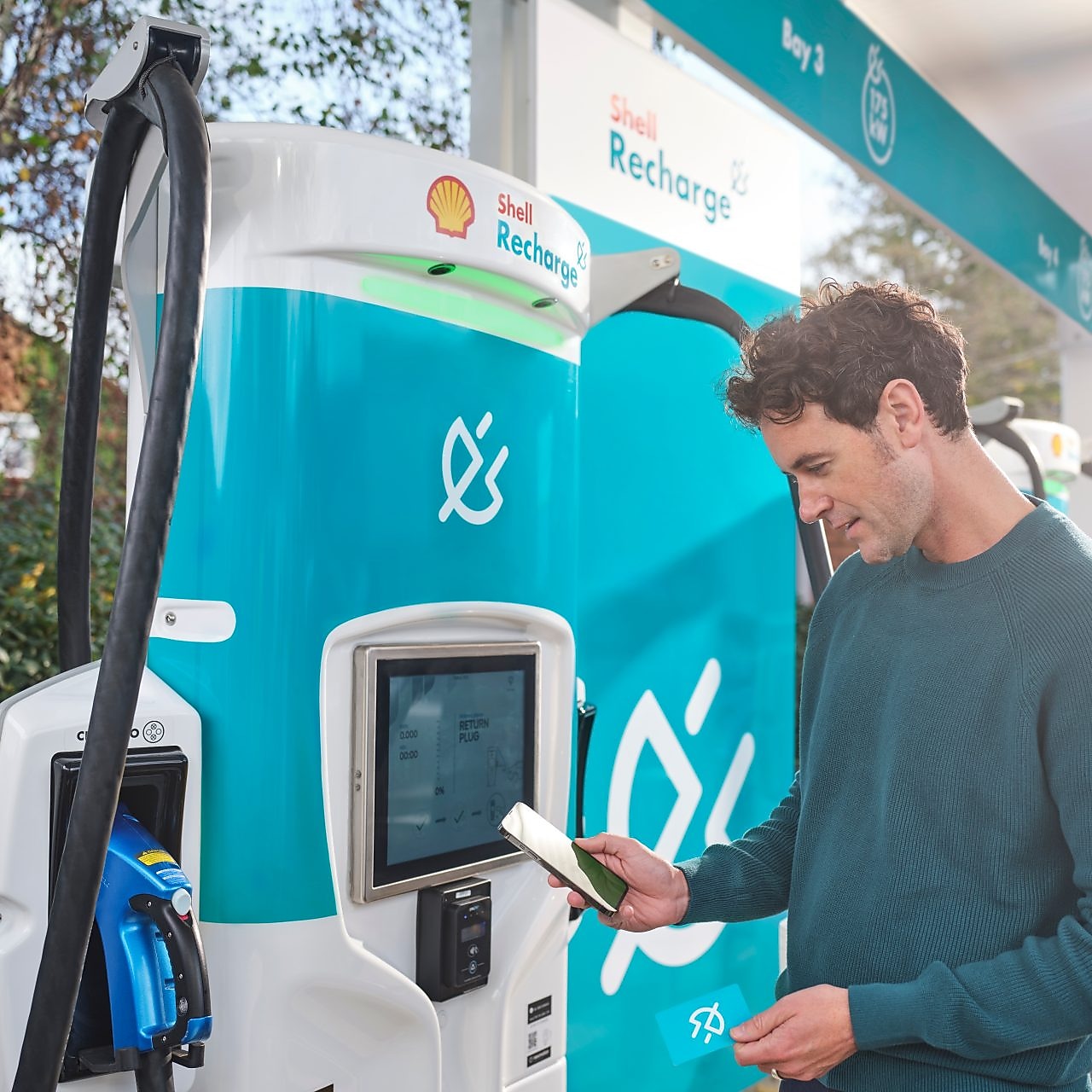 Mladý muž platí pri stojane za využitie nabíjacej stanice Shell Recharge.