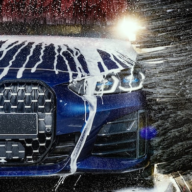 Modré auto v detailnom zábere prechádza cez Shell autoumyváreň.