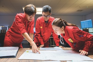 Traja zamestnanci, ktorí si prezerajú výkresy