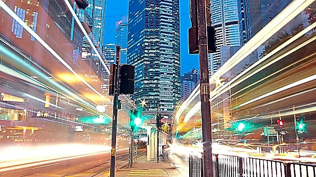 A city scape at night with trailing lights from cars going by.
