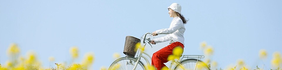 Mladá žena ide na bicykli cez letnú lúku