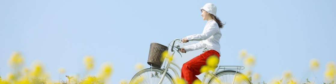 Mladá žena ide na bicykli cez letnú lúku