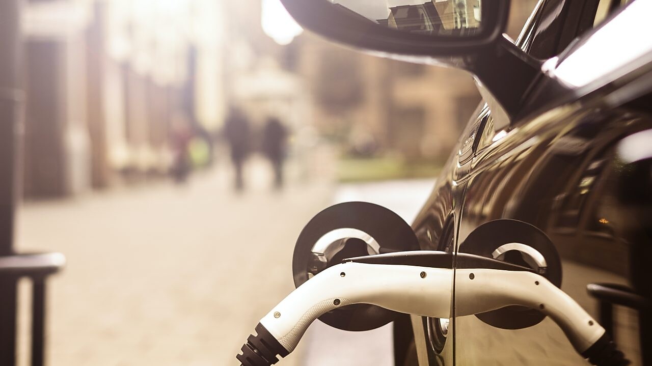 Čierne auto sa nabíja pomocou konektora.