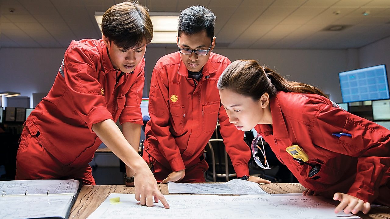 Traja zamestnanci, ktorí si prezerajú výkresy