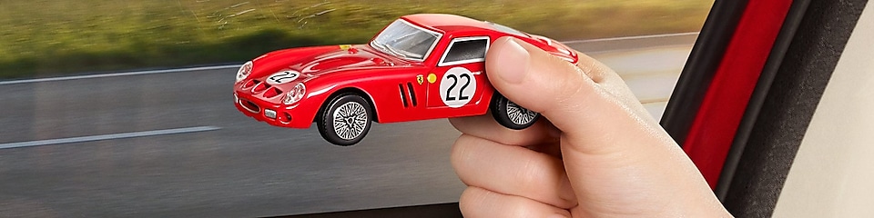 červený model Ferrari v detskej ruke
