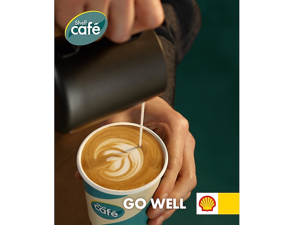 Barista so šálkou kávy v ruke. Logo Shell a Shell Café.