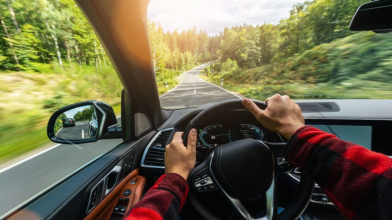 Pohľad vodiča zvnútra auta na čisté čelné sklo a krajinu okolo.