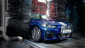 Modré auto v detailnom zábere prechádza cez Shell autoumyváreň.