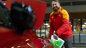 Usmievavá vonkajšia obsluha Shell pomáha zákazníkovi s autom.