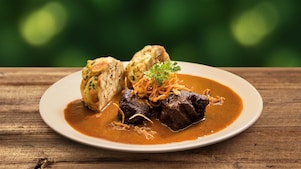 Foto guláša s knedľou na bielom tanieri