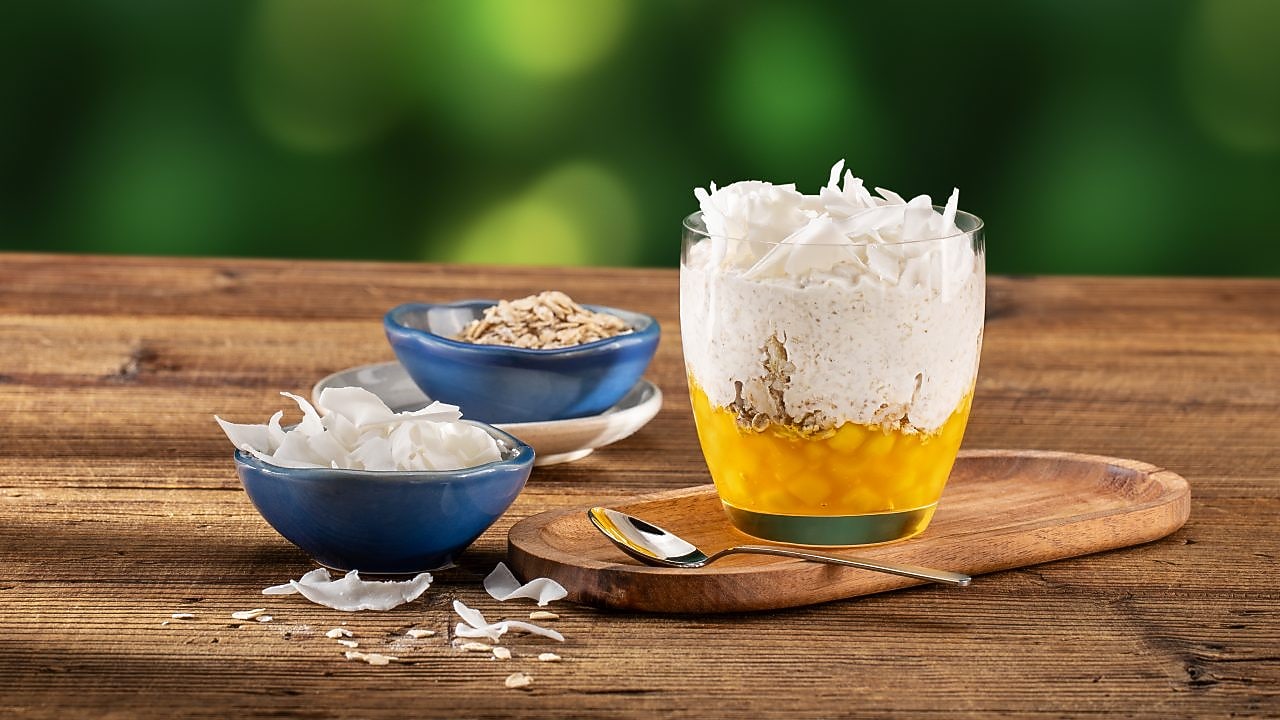 Foto ovsenej kaše v sklenenom pohári s mangom a kokosom