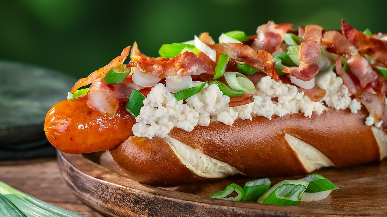 Foto bryndzového hot dogu s anglickou slaninou, jarnou cibuľkou a bryndzou