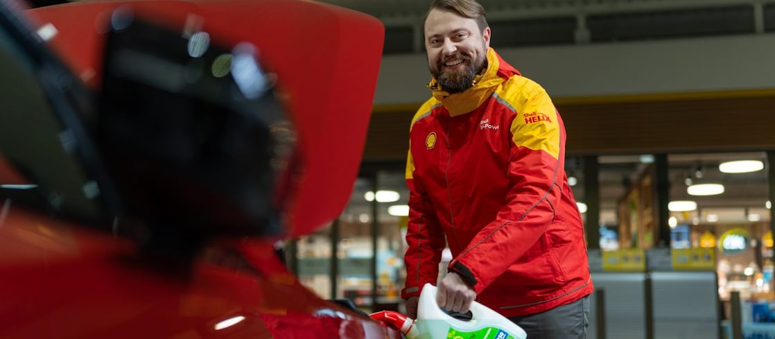 Usmievavý pán z vonkajšej obsluhy doplňuje vodu do ostrekovačov v aute.