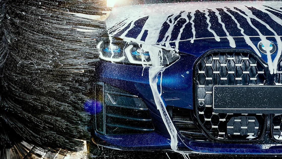 Modré auto v detailnom zábere prechádza cez Shell autoumyváreň.