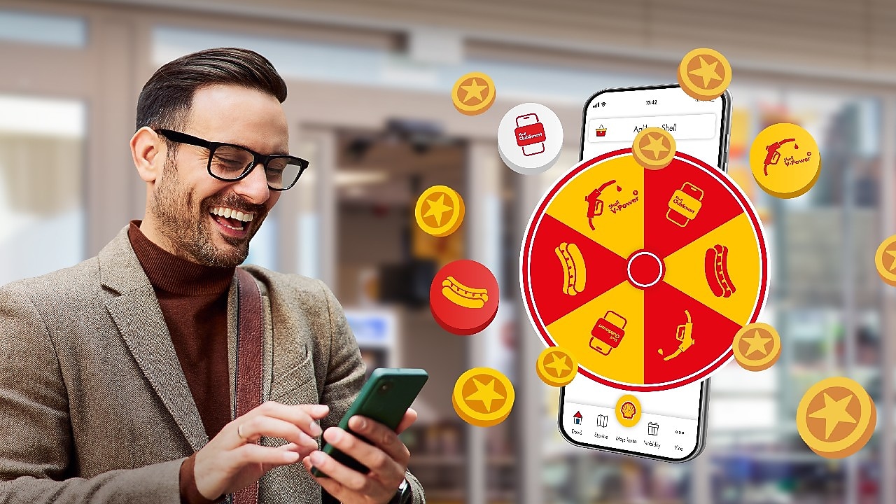 Zákazník s telefónom sa teší pri kolese šťastia.